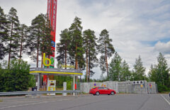 Tankkausaseman ylhäällä on b-kirjain ja takana näkyy punainen Citymarketin pylväs. Tankkaamasta on lähtenyt punainen auto.