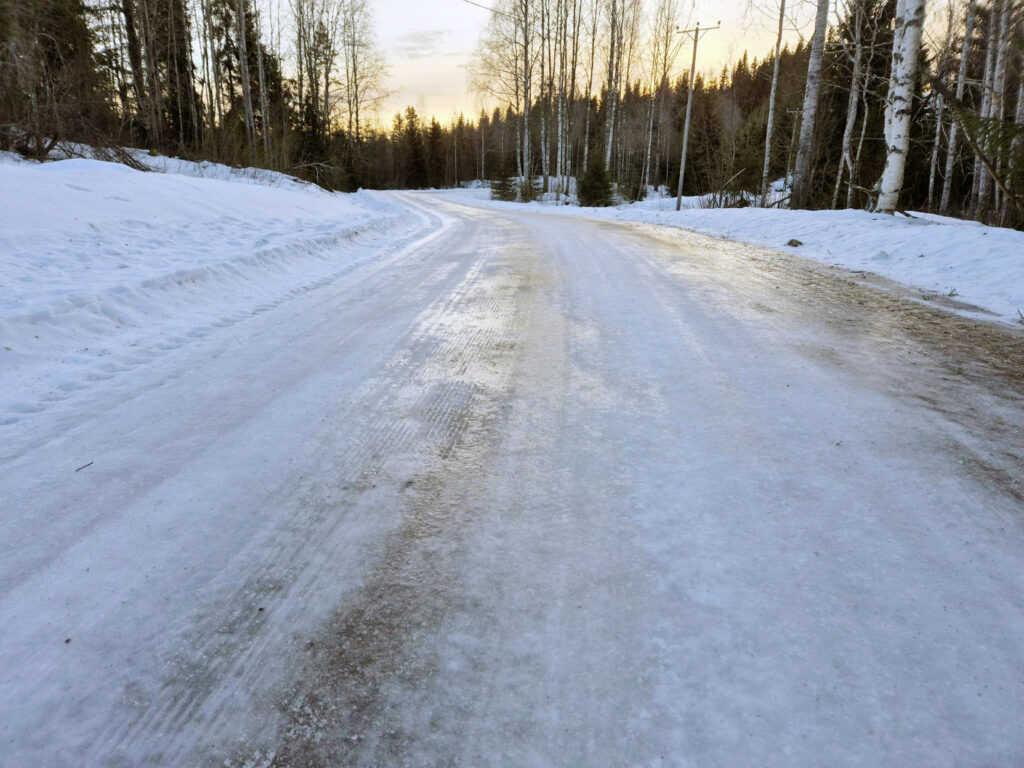 Talvinen tie, joka näyttää todella liukkaalta.